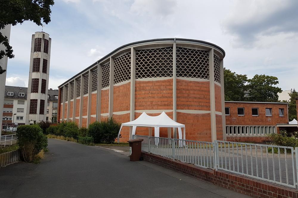 Moderne Backsteinkirche mit freistehendem Turm, Vorplatz und weißem Pavillon unter bewölktem Himmel. (c) Ralf Schmitz Moderne Backsteinkirche mit freistehendem Turm, Vorplatz und weißem Pavillon unter bewölktem Himmel.