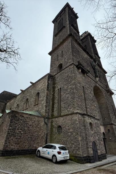 Große Kirche aus Naturstein mit markantem Turm, aufgenommen von einem gepflasterten Vorplatz. (c) Daniel Beinhoff Große Kirche aus Naturstein mit markantem Turm, aufgenommen von einem gepflasterten Vorplatz.