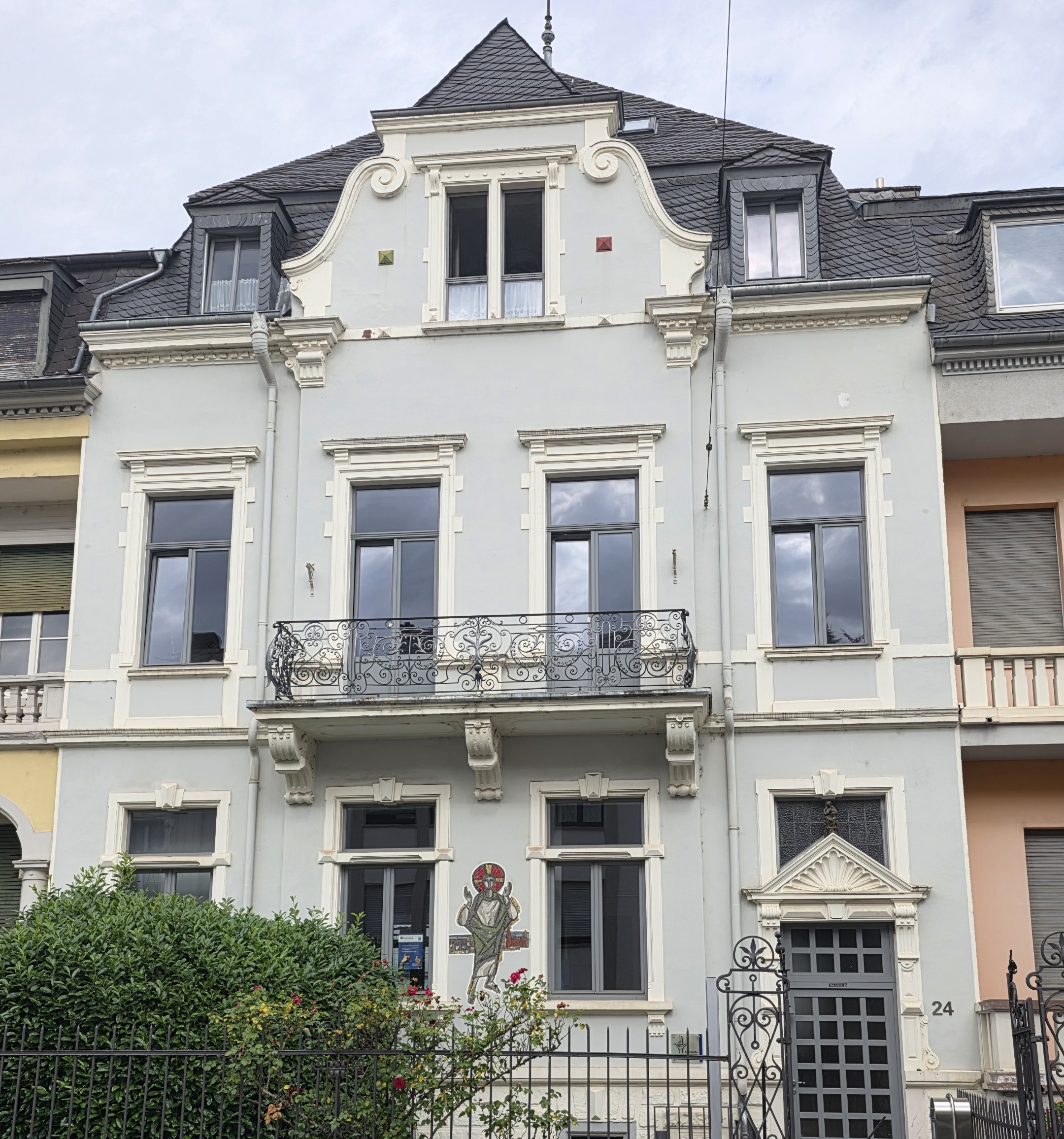 Historisches Wohnhaus mit heller Fassade, Balkon und verzierten Fenstern in einer Häuserzeile.