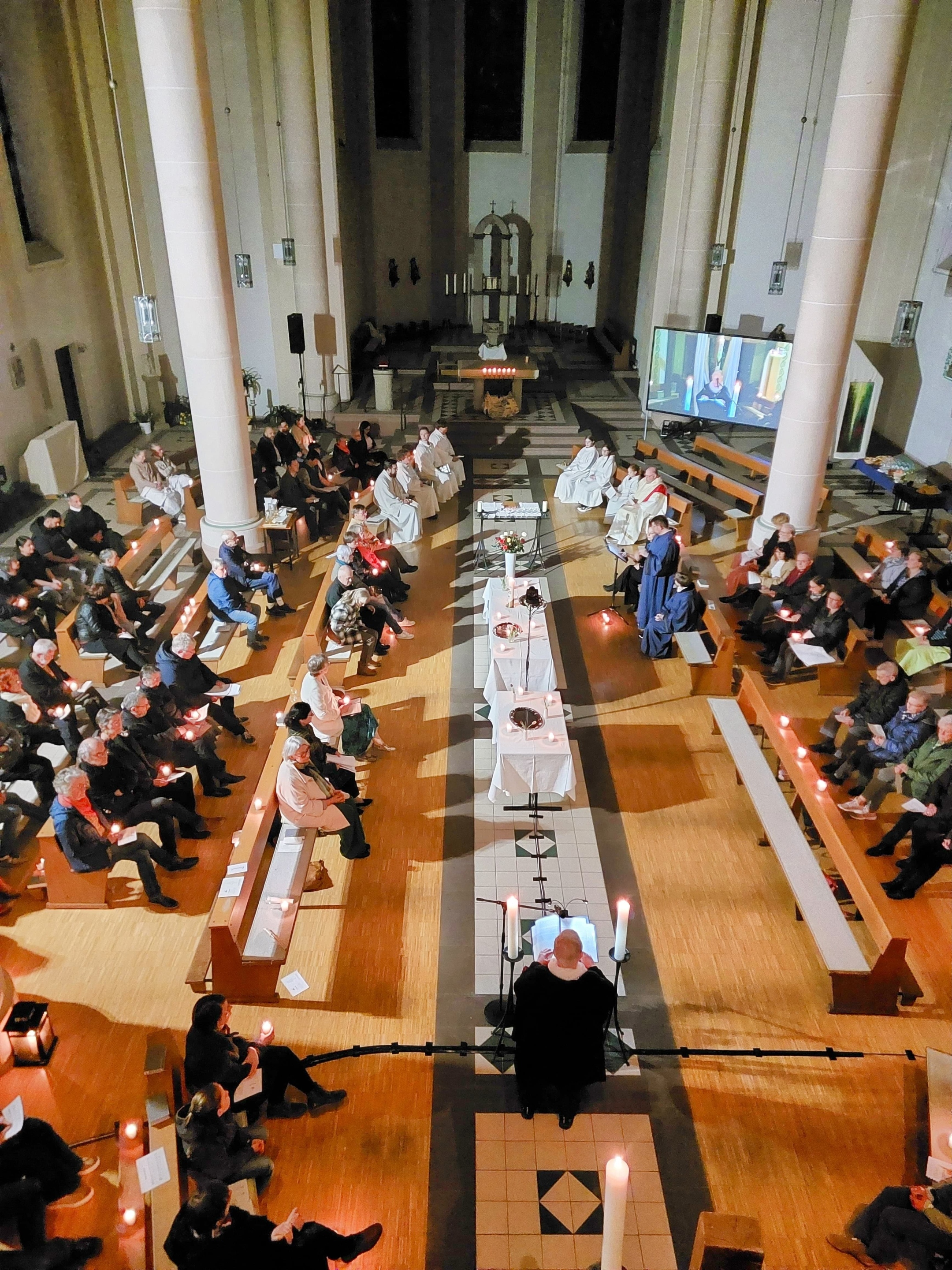 Gemeinde versammelt sich um einen zentralen Altar während eines Gottesdienstes im Kirchenraum.