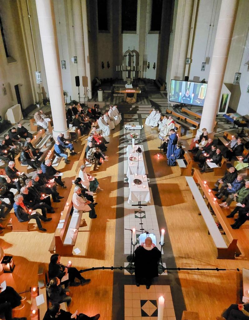 Gemeinde versammelt sich um einen zentralen Altar während eines Gottesdienstes im Kirchenraum.