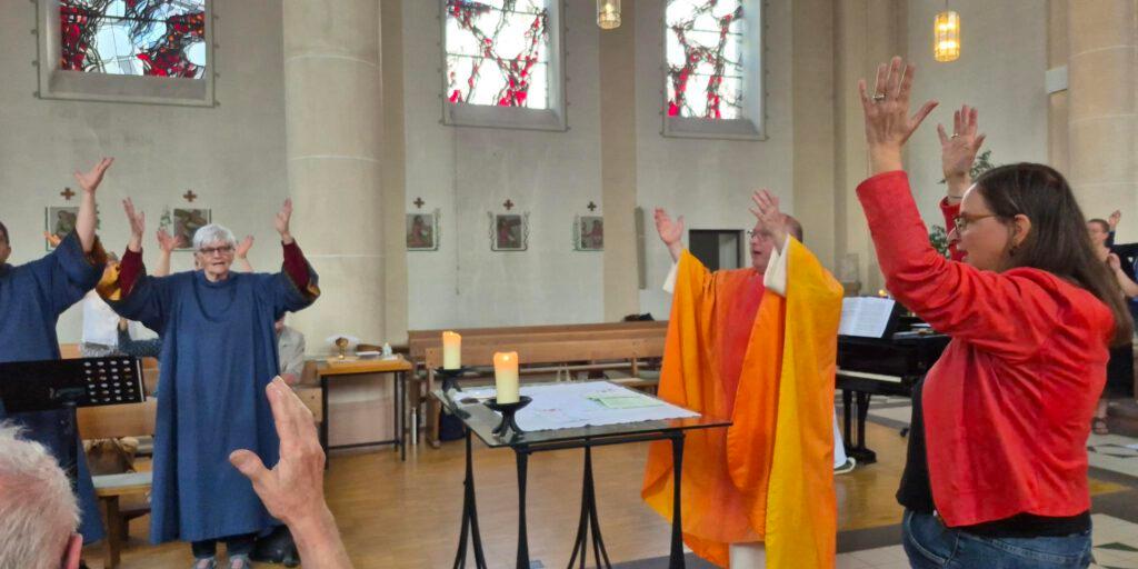 Gottesdienstgemeinde und liturgische Mitwirkende heben gemeinsam die Hände als Gebärden für ein Halleluja.