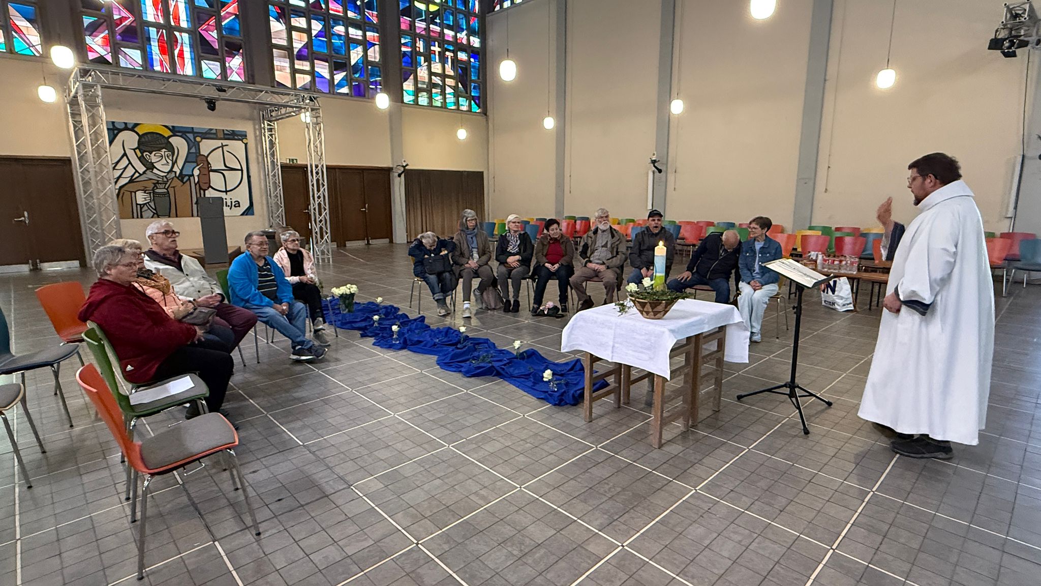 Menschen versammeln sich um einen Tischaltar während eines Gottesdienstes in einer modernen Kirche.