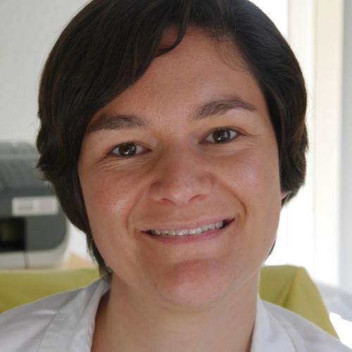 Porträt einer Person mit kurzem dunklem Haar vor hellem Hintergrund.